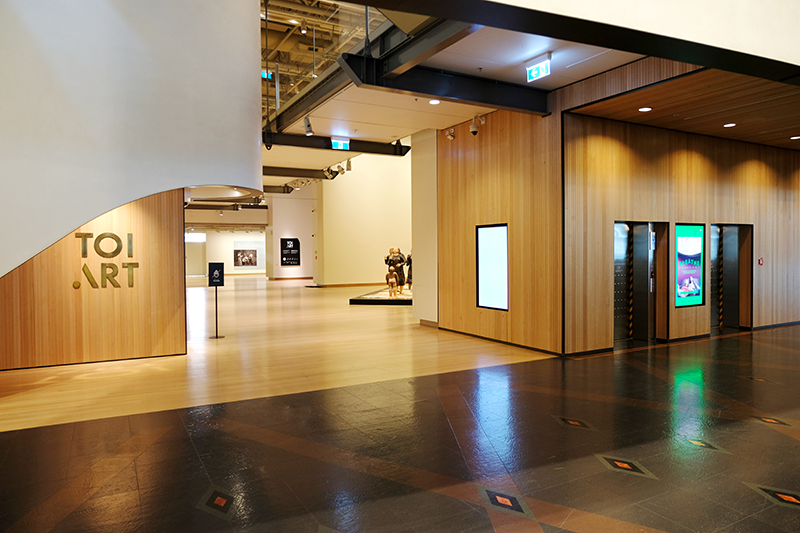 Gallery entrance, with artworks visible and lifts on right.
