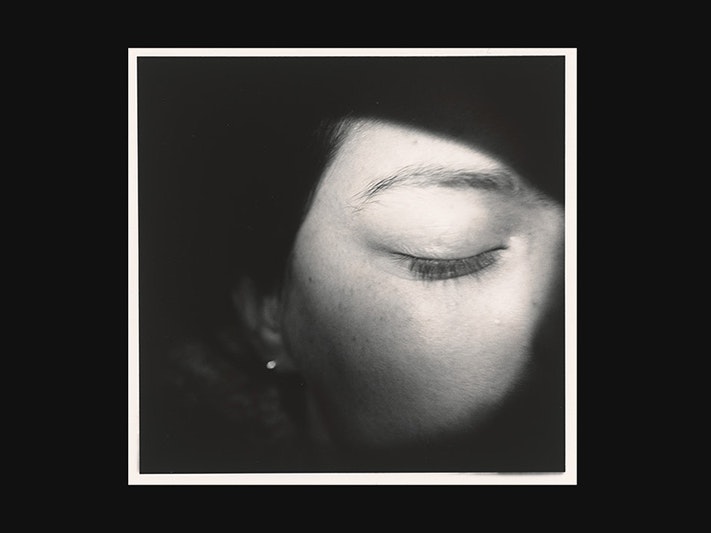 Anne Noble, Night Hawk. No. 7. Untitled, 1982. Purchased 1982 with New Zealand Lottery Board funds. Te Papa (O.002988) A black banner with a photo on the right-hand side of a close up on a woman's face with her eye closed.