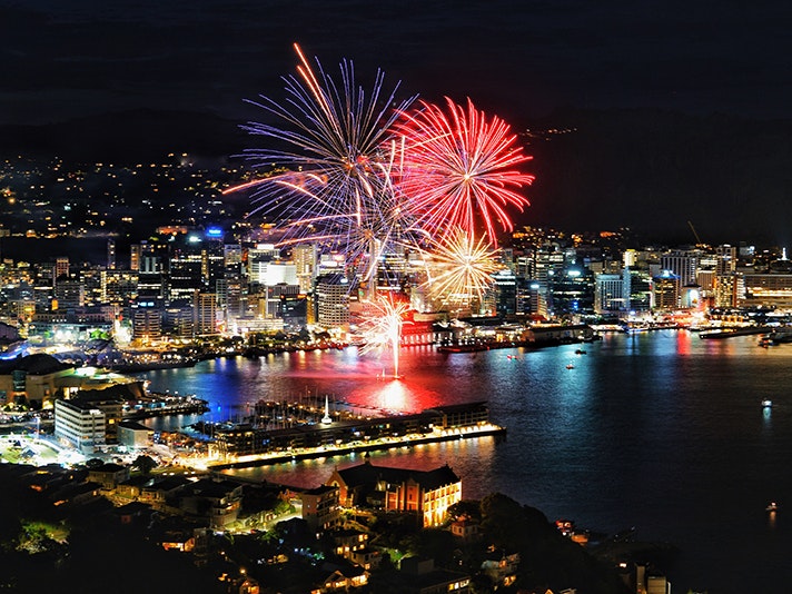 Photo by Jun Yamog, courtesy of Asian Events Trust A night-time photograph of Wellington city with large fireworks exploding over the harbour.