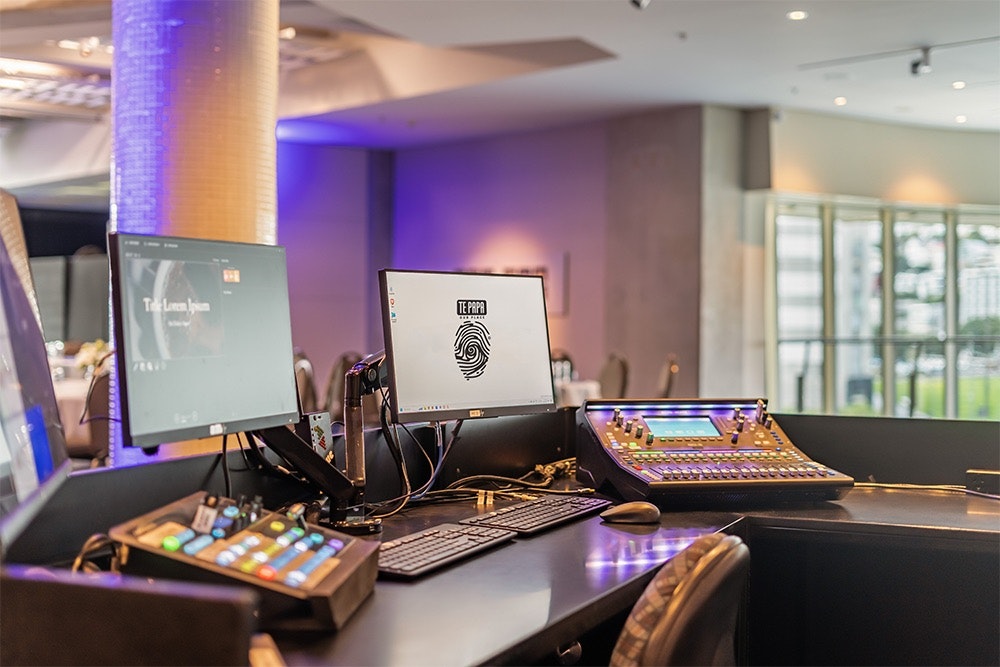A desk with a computer screen and keyboard and several audio and lighting mixing desks.