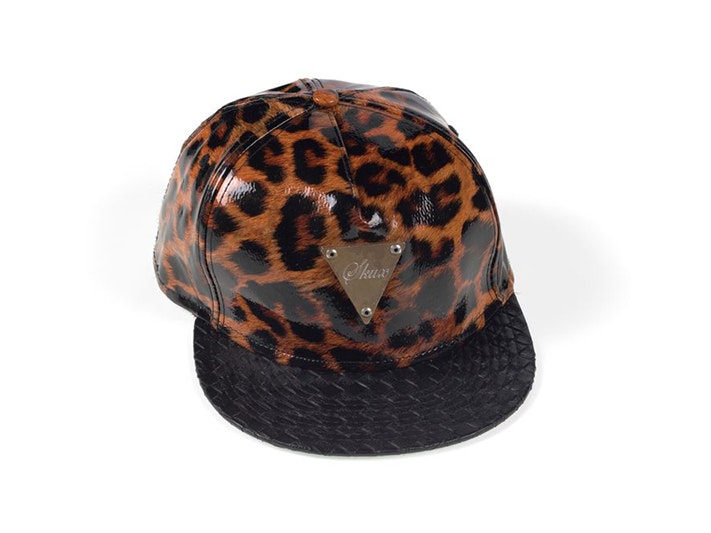 Ricky Baker outfit; Skux cap. Kristin Seth; costume designer. Gift of Majestical Pictures Limited, 2019. Te Papa (GH018347/10) A brown tiger-print cap with a black rim and a label sewn onto it that says "skux".