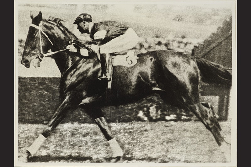 A black and white photo of a rider and horse running in a race.