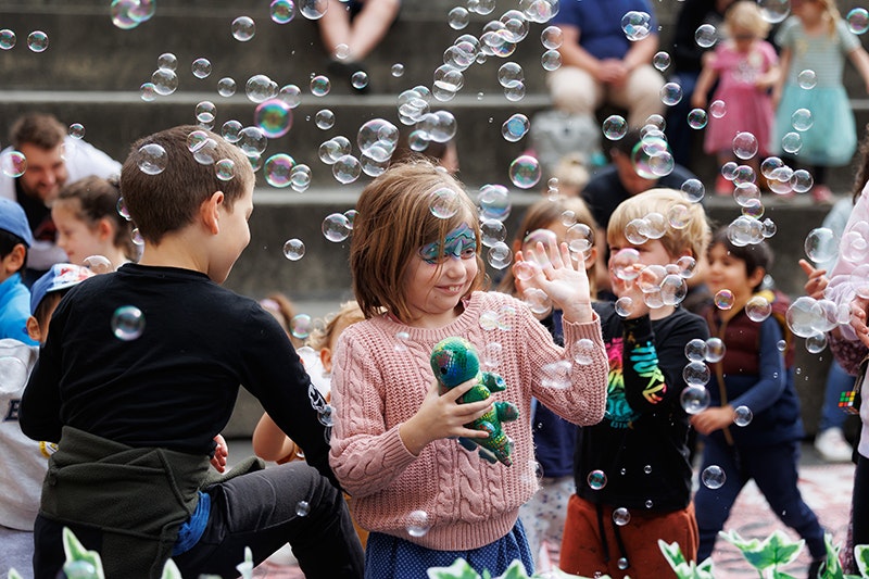 Kids outside with painted faces and bubbles all around them.